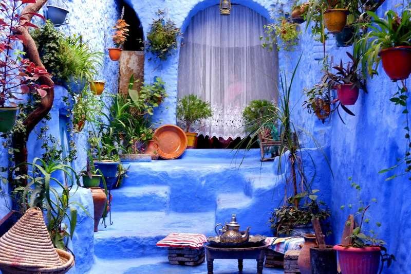 Serene blue courtyard in Chefchaouen with traditional tea setting - romantic Morocco escape