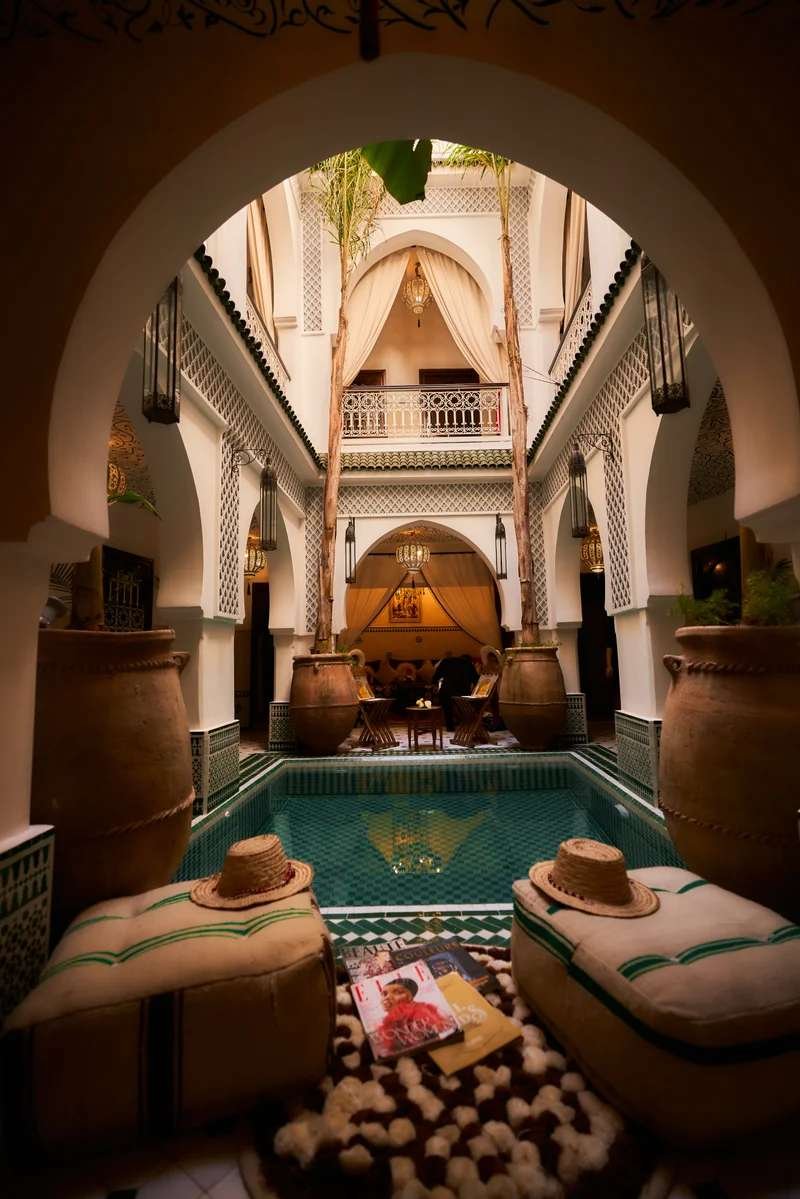 Intimate riad interior with turquoise pool, traditional arches and lush courtyard garden