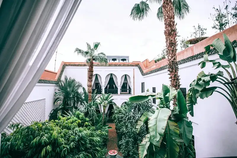 Lush courtyard garden of a Moroccan riad, the kind of home where families gather for Eid visits with tea and sweets