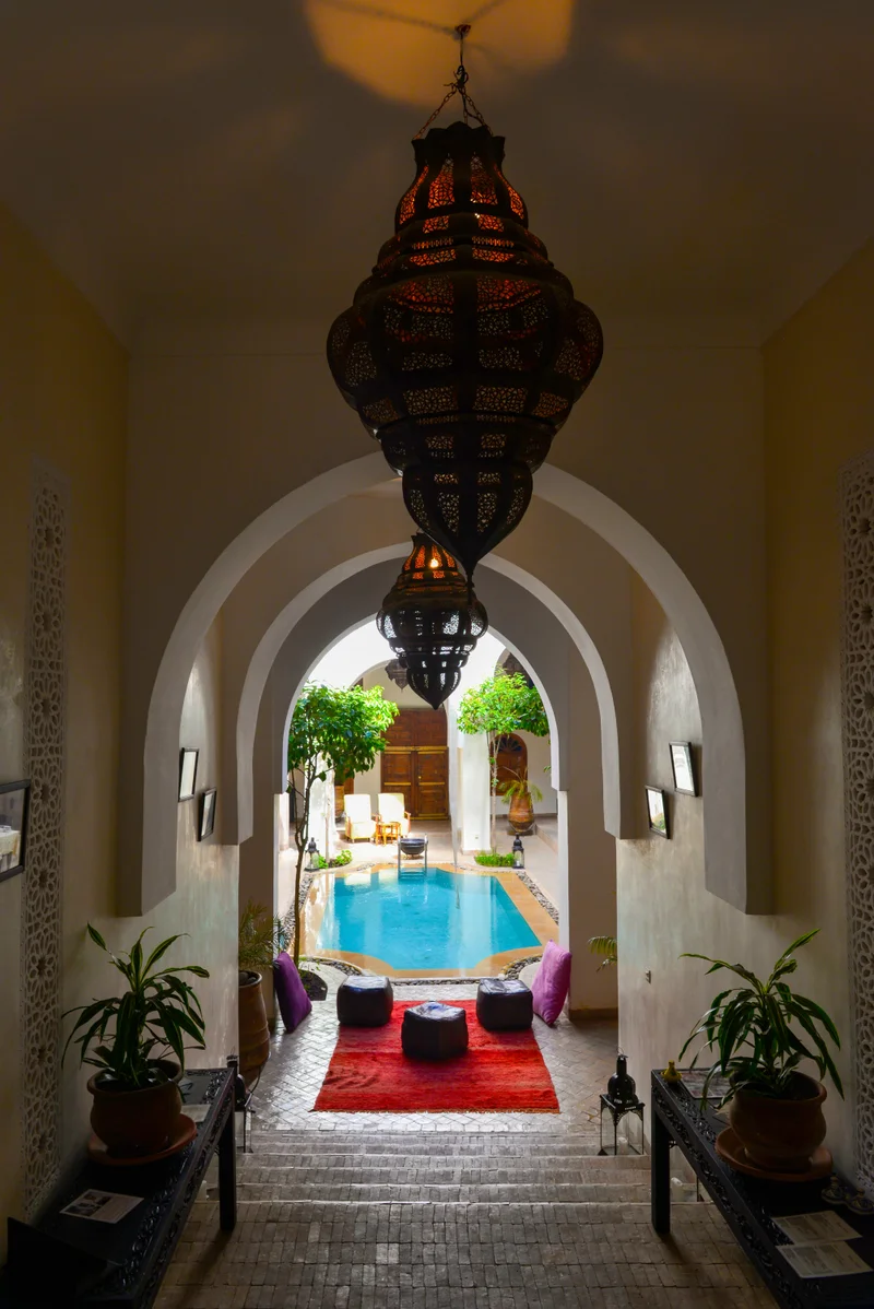 Elegant Marrakech riad courtyard with decorative pool, ornate horseshoe arches, and traditional lanterns showing the city's reliable luxury accommodation and polished tourism infrastructure