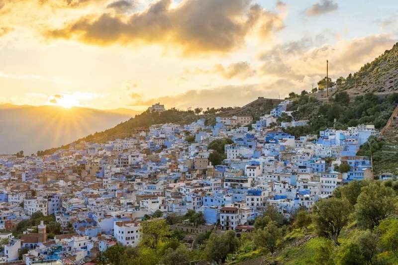 Panoramic view of Chefchaouen at sunset with warm light over blue houses and Rif Mountains - Morocco's blue pearl in northern region