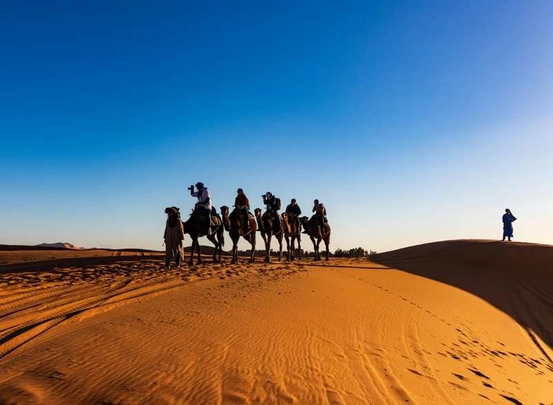 Romantic camel trek through golden Sahara dunes at sunset - quintessential honeymoon experience