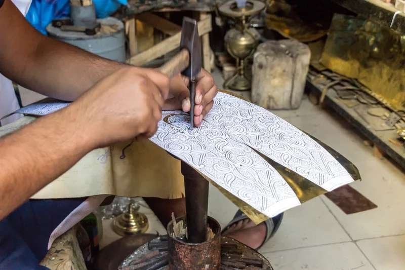 Moroccan artisan engraving intricate motifs on brass in a traditional souk workshop.